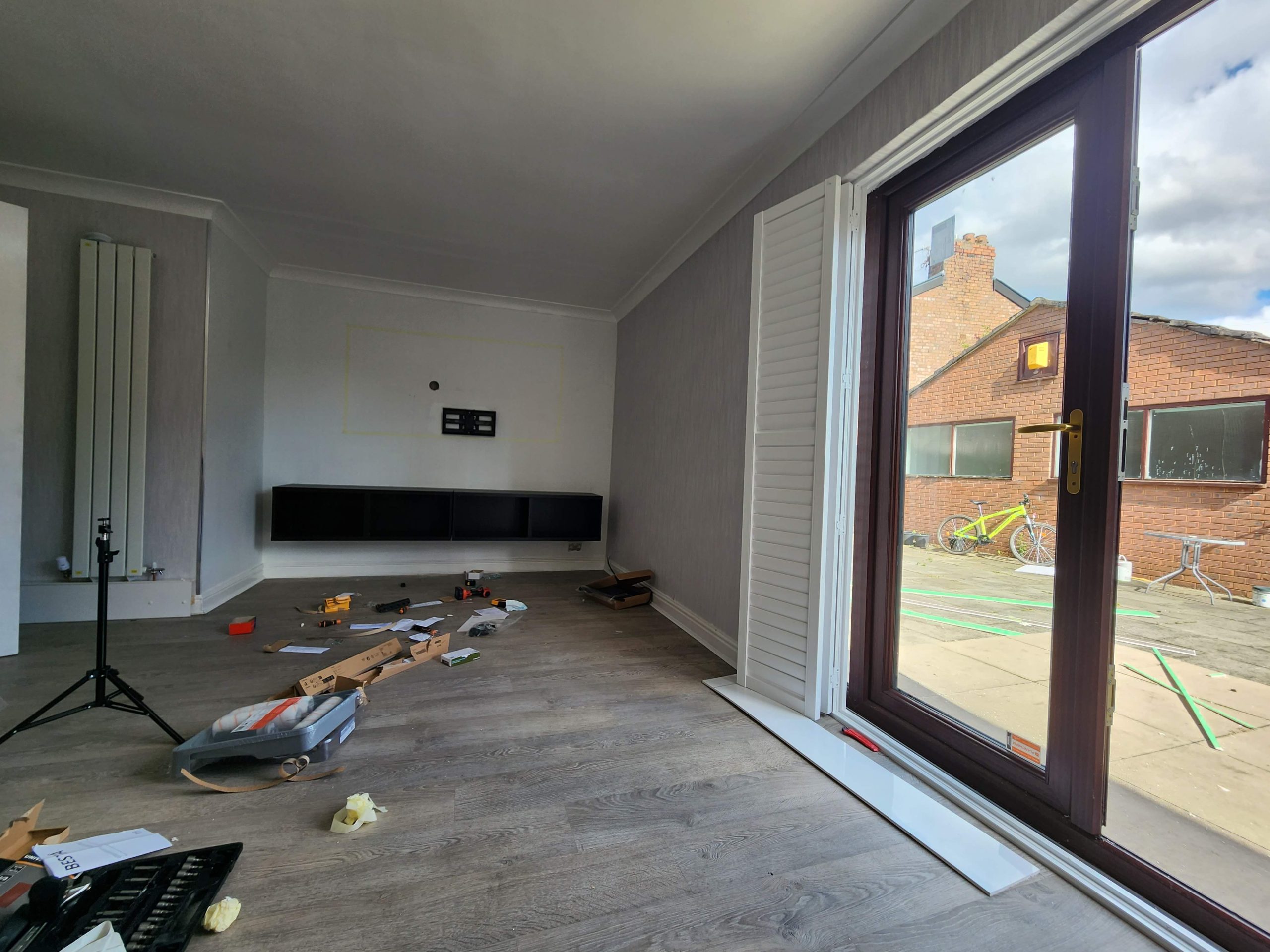 Living room stripped back before the media wall work, with tools on the floor