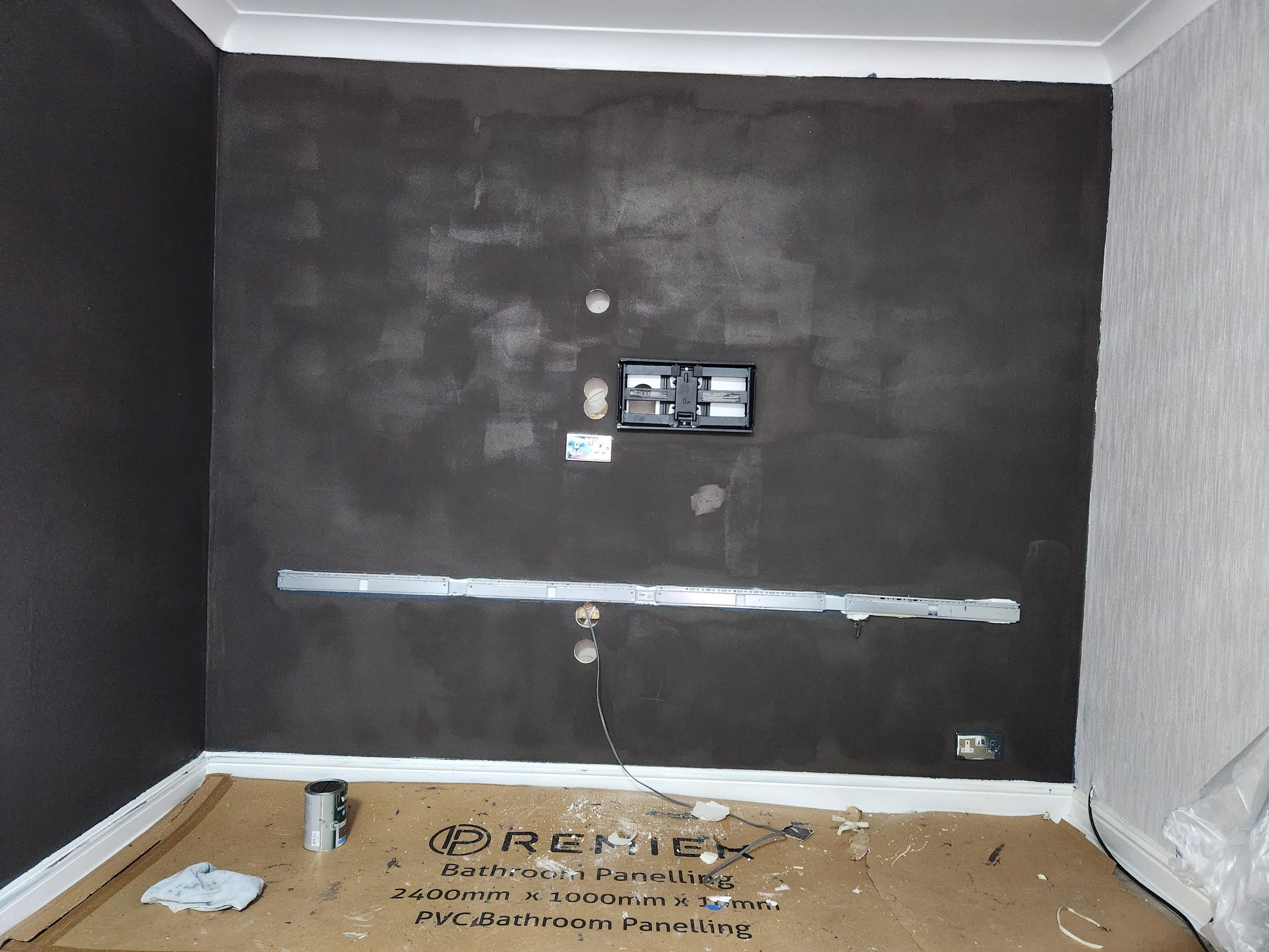 Feature wall prepared with a dark finish and TV bracket rail, ready for panelling